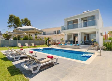 Luxury villa with a private swimming pool, sun loungers, and outdoor patio area under a blue sky.