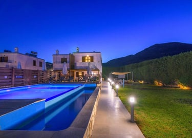 Luxury villa rental with private swimming pool and garden at night under a blue sky.