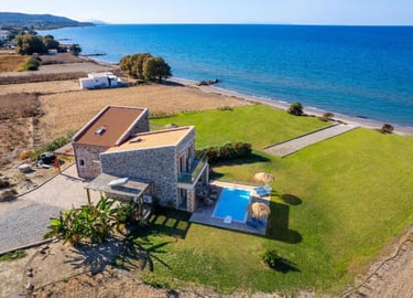 Luxury stone beachfront villa with private swimming pool and green lawn overlooking the blue Mediterranean sea.