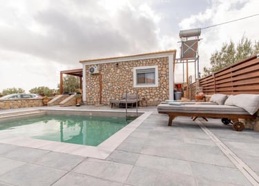Luxury stone villa rental with private swimming pool and cushioned sun loungers on a modern patio.