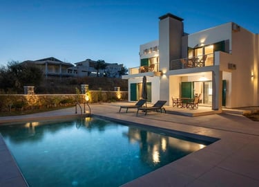Luxury modern villa at dusk with an illuminated private pool and outdoor patio lounge.