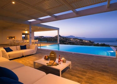 Luxury villa patio with infinity pool, lounge seating, and sunset ocean views.