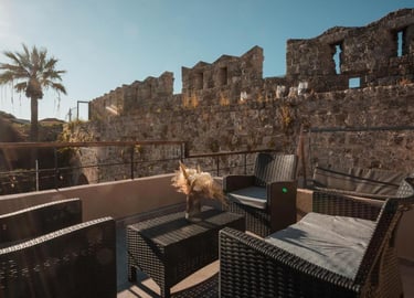 Luxury patio furniture on a rooftop terrace overlooking the historic stone walls of Rhodes Old Town.