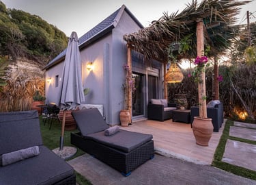 Luxury vacation cottage with a tropical patio, wicker lounge chairs, and a thatched pergola.