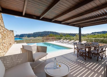 Luxury villa terrace with private pool, outdoor dining set, and scenic ocean views in Greece.