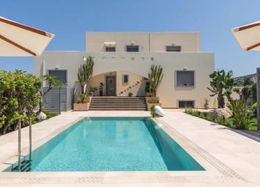 Luxury modern villa with a turquoise swimming pool, sun loungers, and desert landscaping under a clear blue sky.