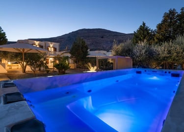 Luxury villa rental with an illuminated blue swimming pool and mountain views at dusk.