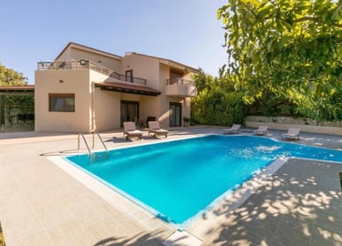 Luxury vacation villa with a large private outdoor swimming pool and sun loungers.