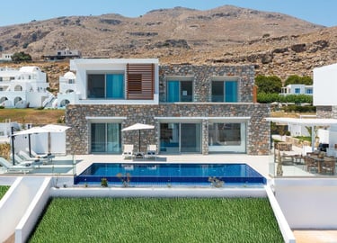 Luxury stone villa in Rhodes with an infinity pool, sun loungers, and scenic mountain views.
