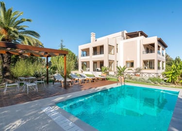 Luxury Mediterranean villa with private swimming pool, sun loungers, and outdoor dining pergola.
