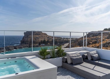 Luxury hotel rooftop terrace with a private hot tub and lounge beds overlooking the Mediterranean Sea.