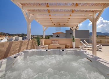 Luxury rooftop terrace with bubbling hot tub, wooden pergola, and scenic city views.