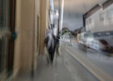 Abstract Cape Town street photograph showing a layered impression of a woman in a headscarf walking past cars and buildings