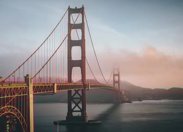 Golden Gate Bridge in San Francisco shrouded in morning fog during a golden hour sunrise.