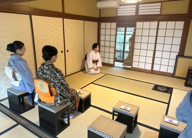 Two women wearing kimono sitting on chairs during a Japanese tea ceremony experience
