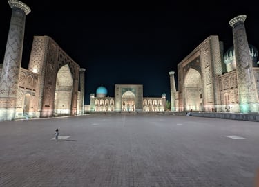 The illuminated tiled faces of the madrasas at the Registan at night in Samarkand, Uzbekistan.