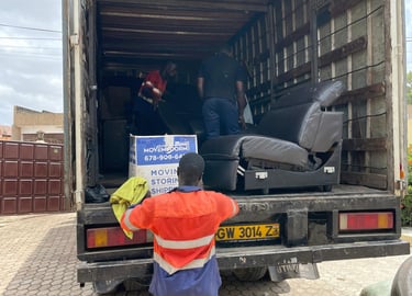 A professional mover in an orange high-visibility vest with reflective strips and blue pants, holdin