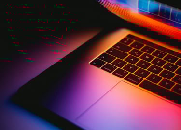 Laptop slightly open with warm colors shining through. Photo by Andras Vas on Unsplash.com