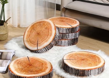 Set of round decorative tree stump floor cushions arranged on a white faux fur rug in a living room.