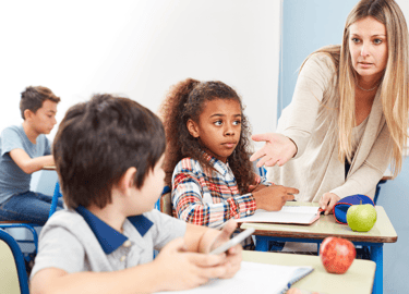 Teacher asking boy for his cell phone in the classroom.