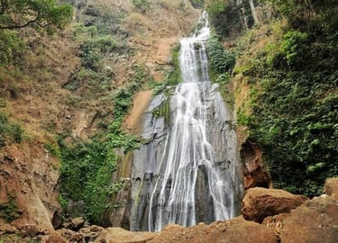 Hikers approaching Mataru Waterfall through lush forest in alor