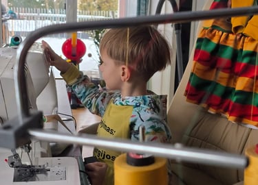 Berniukas siuva su siuvimo mašina