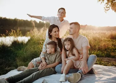 large young Caucasian family smiling at a sunset picnic