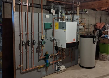 A utility room featuring a residential boiler system with copper piping, a water heater, and various HVAC components
