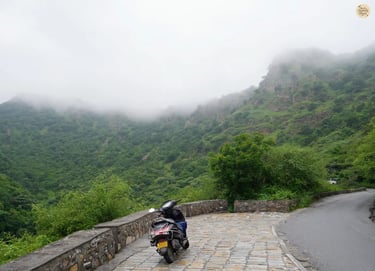 Curved forest trail on the hills leading up to Sajjangarh Fort udaipur under cloudy skies.