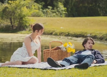 a man and woman sitting on a blanket in the grass