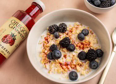 a bowl of cereal with berries and a bottle of syrup