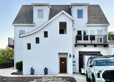 A French Revival architecture home with sloping roof lines, high dormers, and cantilevered decks.