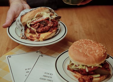 Dan holding a Winnipeg Fat Boy style burger and chips over a table.