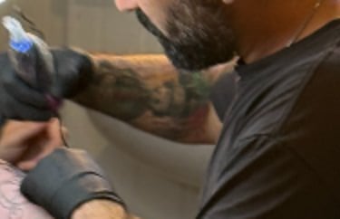 Tattoo Artist doing tattoo on the arm of a client