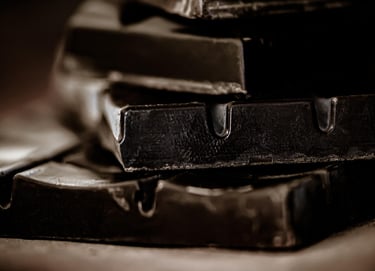Close-up of stacked dark chocolate bars with a moody, cinematic aesthetic and soft lighting.
