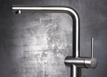 brushed chrome kitchen mixer tap against metal background