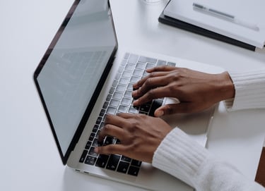 a person sitting at a table with a laptop and a glass of water