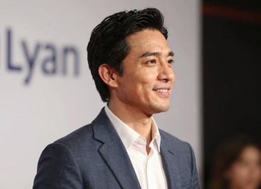 A medium shot of Lyan Galindo from the side, looking towards a warm light source with a gentle smile. The style is professional and inviting, with a soft-focus background that includes hints of a stage setting. The palette focuses on #1A2D3A and #E6EBE0.