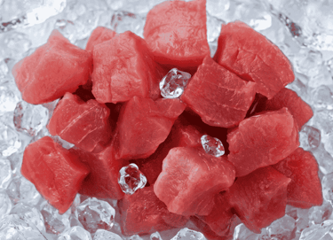 Fresh raw beef cubes for stew sitting on a bed of crushed ice cubes.