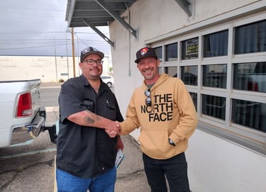 two men shaking hands in front of a building