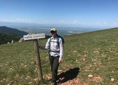 a woman in a hat and backpack standing on a mountain
