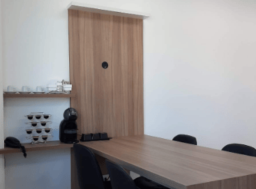 sala de reunião e projetos com mesa, cadeiras e um cantinho do café