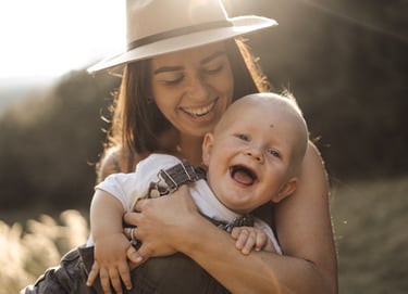 Mother holding her son in the arms and laughing during sunset