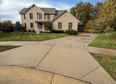 Modern two-story brick luxury home with a large concrete driveway and manicured green lawn.