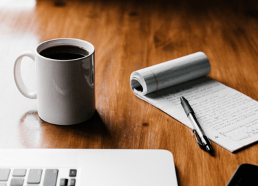 a cup of coffee and a notebook on a table
