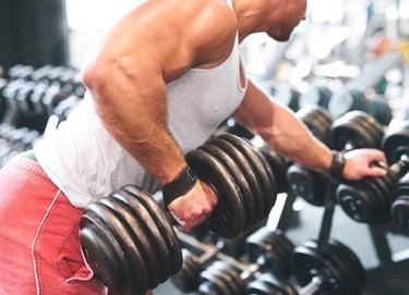 A muscular man performing a single-arm dumbbell row for back strength training in a gym setting.