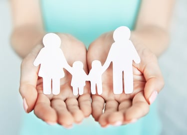 a woman holding two hands with paper cutouts of a family