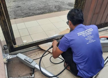 Suasana Automation technician repairing and installing automatic gate motor system.