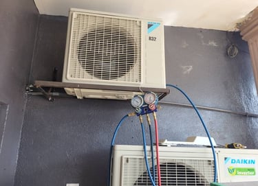 Suasana Aircond technician checking refrigerant pressure for Daikin repair.