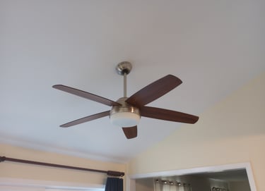 A five bladed ceiling fan with dark brown blades and a light is attached to a white ceiling